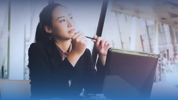 Asian woman thinking through a solution while on her laptop