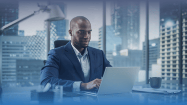 Successful Black businessman in tailored suit working on laptop computer.