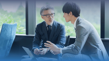 Two Asian businessmen discuss AI in recruitment.