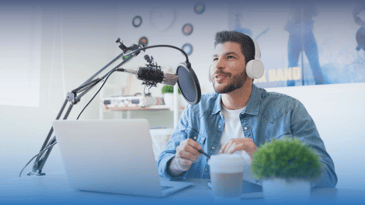 Man at his home office with podcast equipment by his laptop