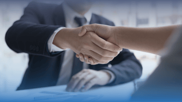 Pair of people shaking hands across a conference table
